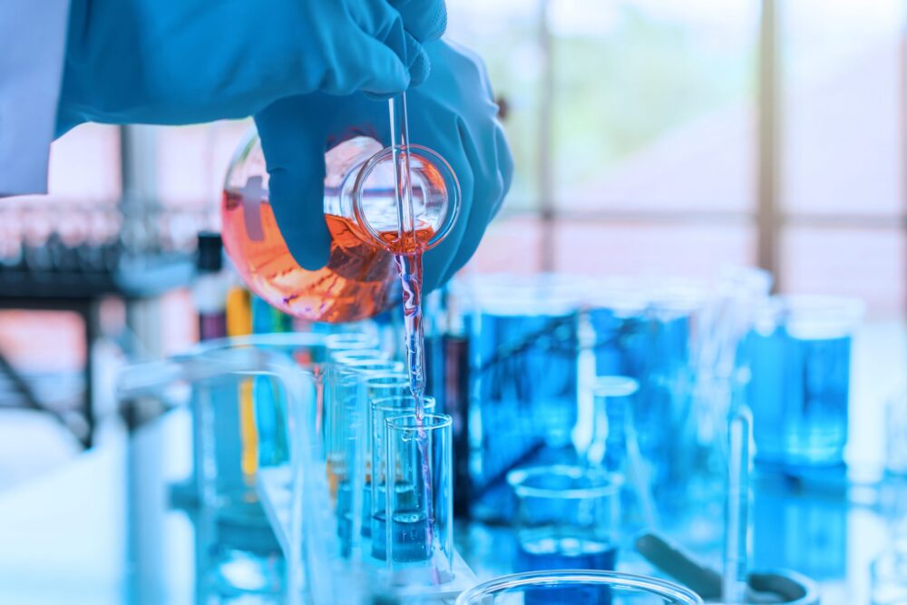 scientist with equipment and science experiments, laboratory glassware containing chemical liquid for research or analyzing a sample into test tube in laboratory.